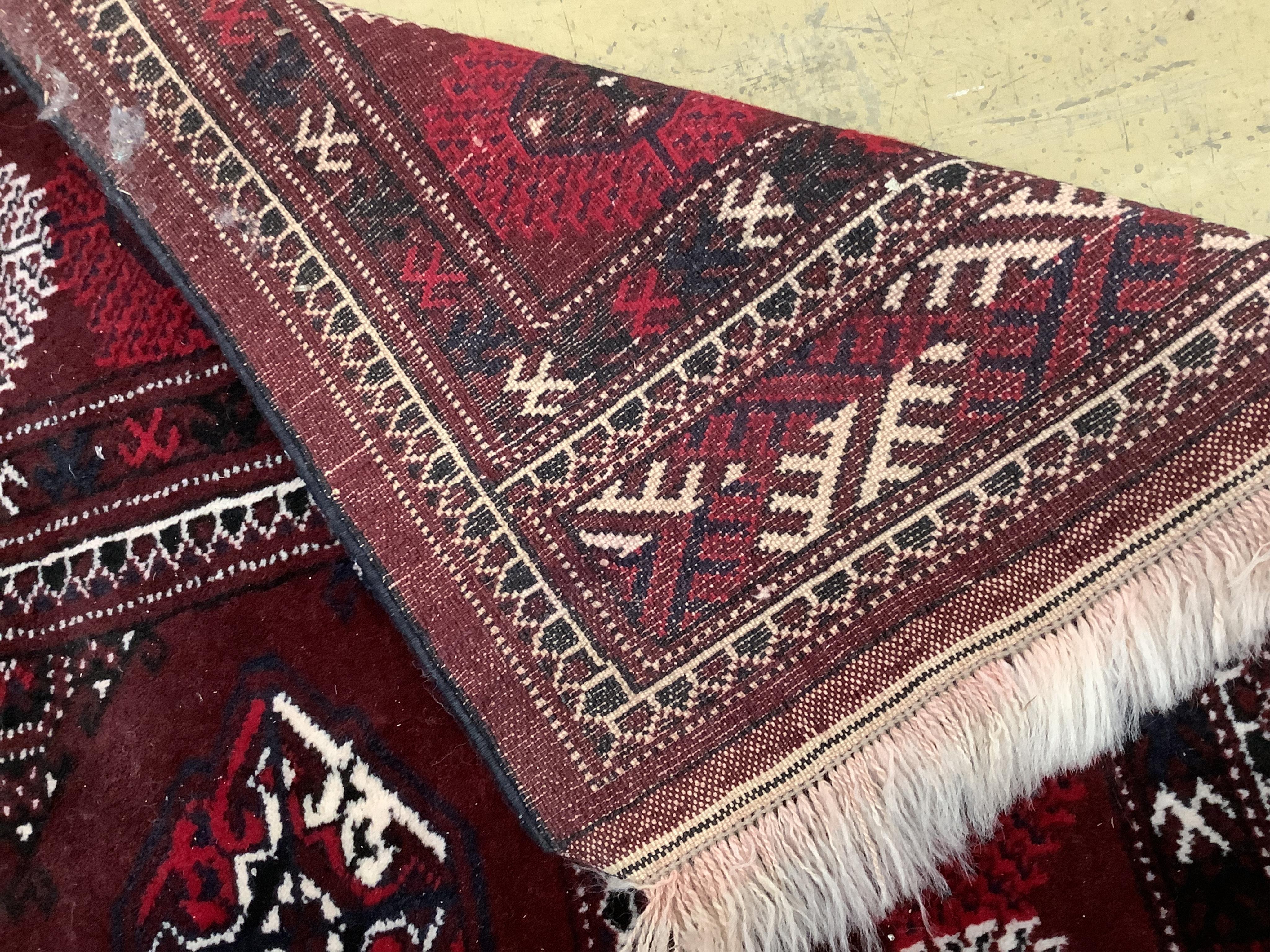 A Turkoman burgundy ground carpet, 386 x 234cm